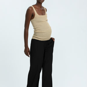 Woman wearing black linen trousers and beige vest top
