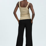 Woman wearing black linen trousers and beige vest top