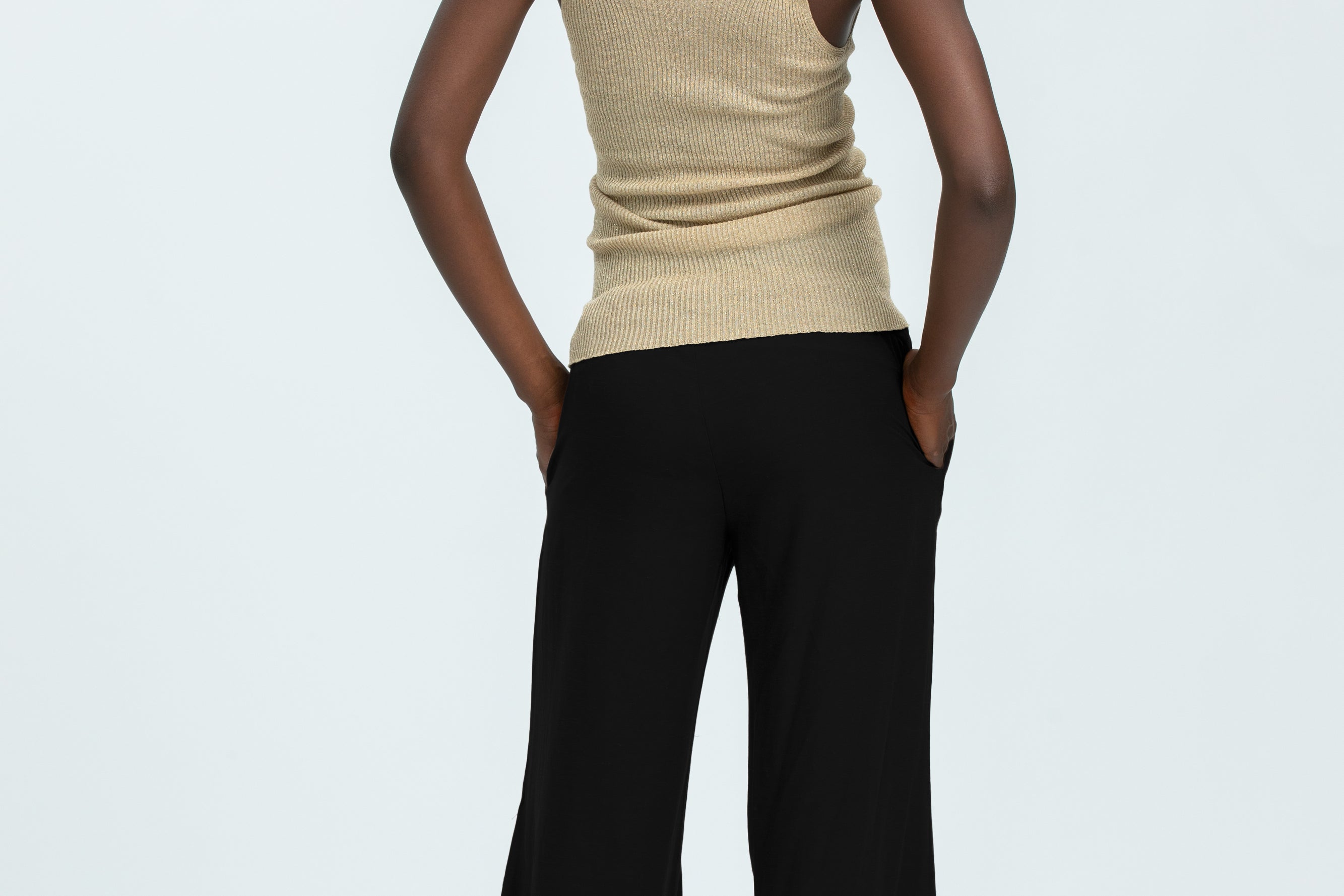 Woman wearing black linen trousers and beige vest top