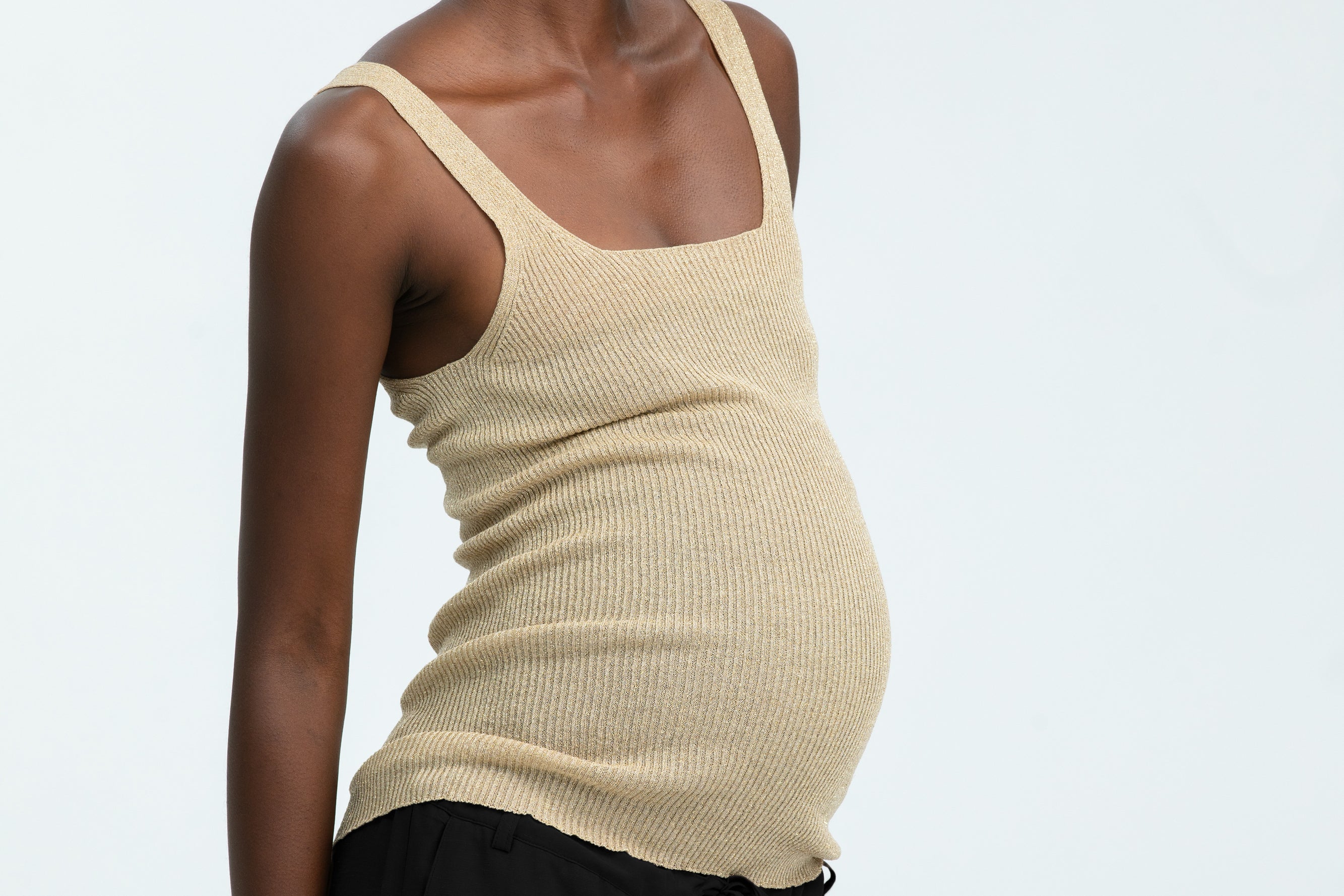 Woman wearing black linen trousers and beige vest top