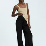 Woman wearing black linen trousers and beige vest top