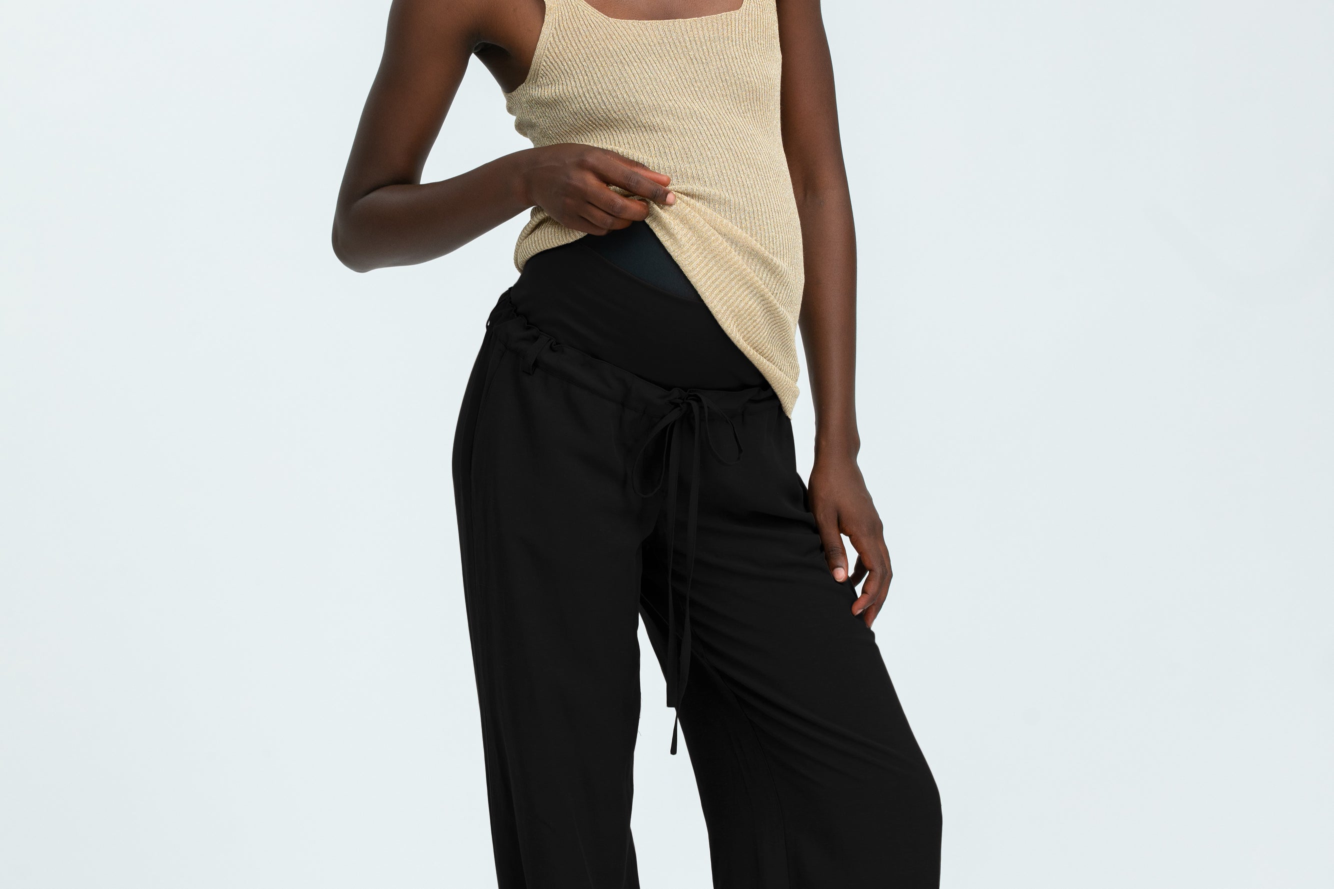 Woman wearing black linen trousers and beige vest top