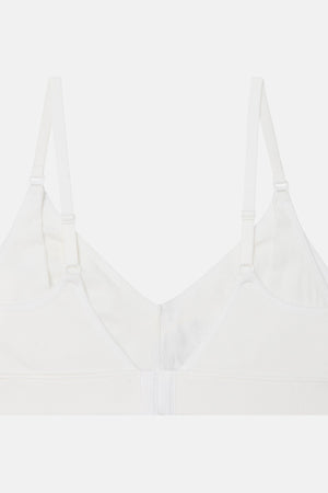 A white seamless bralette with adjustable shoulder straps and a center front closure, shown flat against a light gray background.