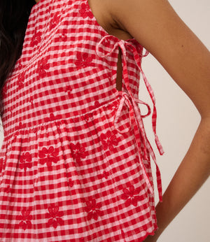 Red and white checkered sleeveless top with floral patterns on a neutral background