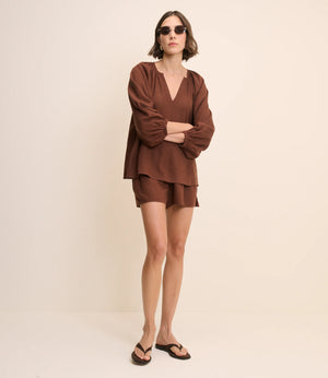 Woman wearing a brown outfit on a beige background