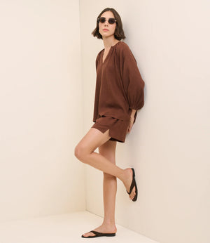 Woman wearing a brown outfit on a beige background
