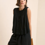 Woman wearing a black sleeveless dress against a beige background