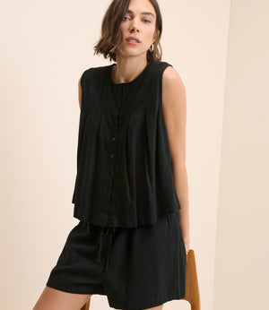 Woman wearing a black sleeveless dress against a beige background