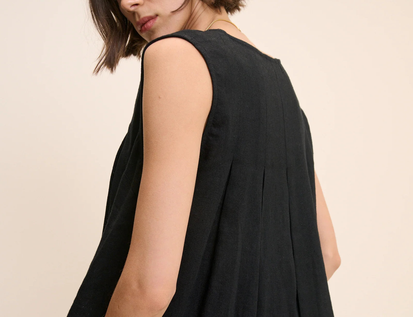 Woman wearing a black sleeveless top against a beige background