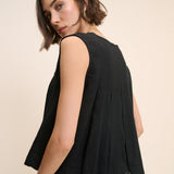 Woman wearing a black sleeveless top against a beige background