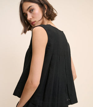 Woman wearing a black sleeveless top against a beige background