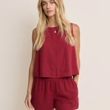 Woman wearing a red sleeveless top and shorts set against a beige background