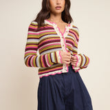 Woman wearing a colorful striped sweater and navy shorts on a beige background
