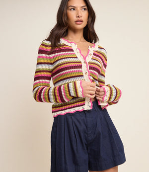 Woman wearing a colorful striped sweater and navy shorts on a beige background