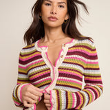 Woman wearing a colorful striped crochet cardigan against a neutral background
