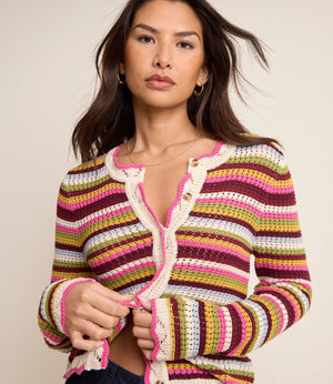 Woman wearing a colorful striped crochet cardigan against a neutral background