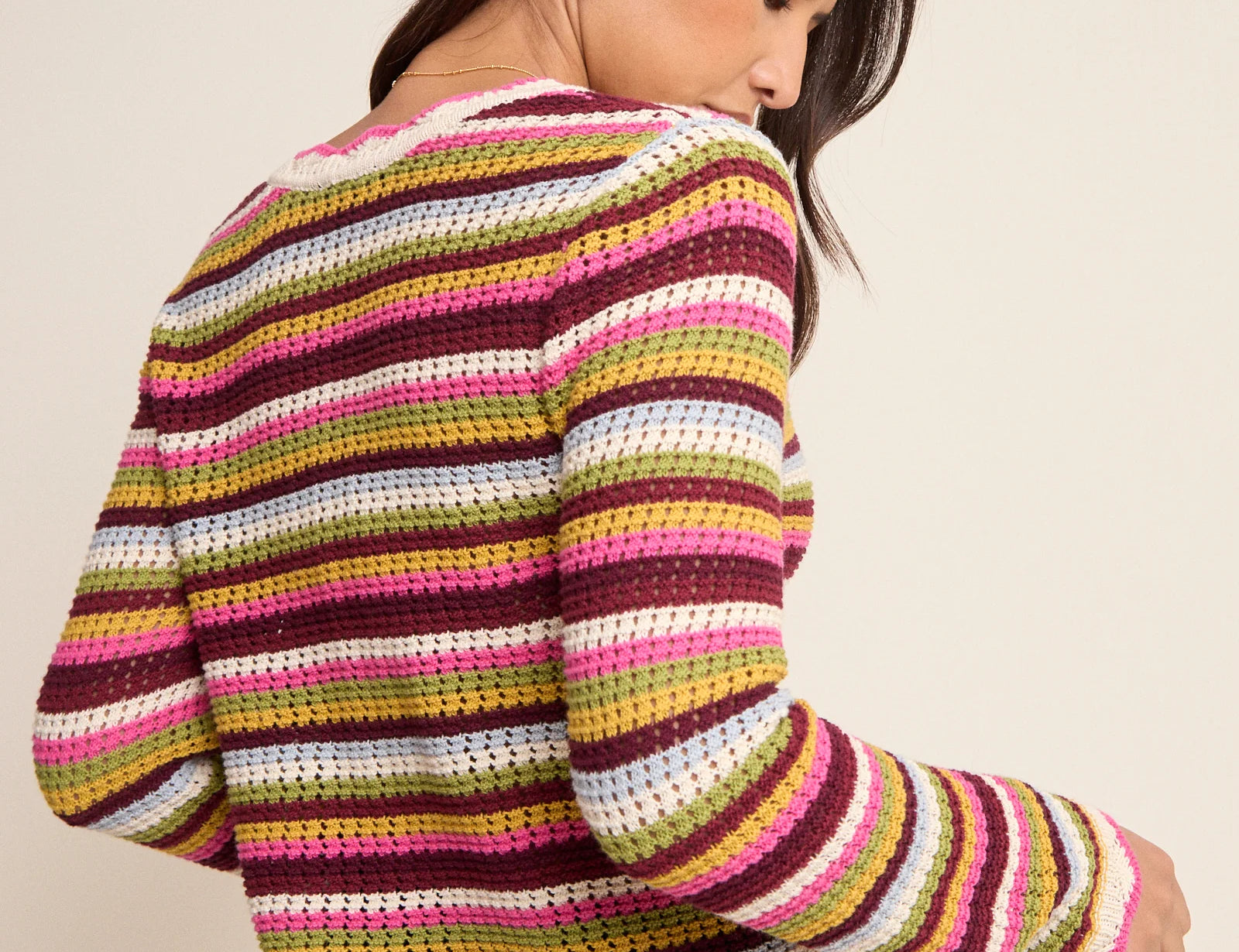 Woman wearing a colorful striped sweater against a plain background