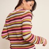 Woman wearing a colorful striped sweater against a plain background