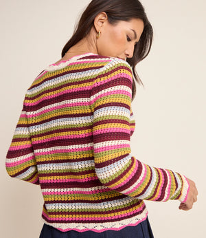 Woman wearing a colorful striped sweater against a plain background