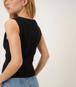 Woman wearing a black sleeveless top and blue jeans against a white background