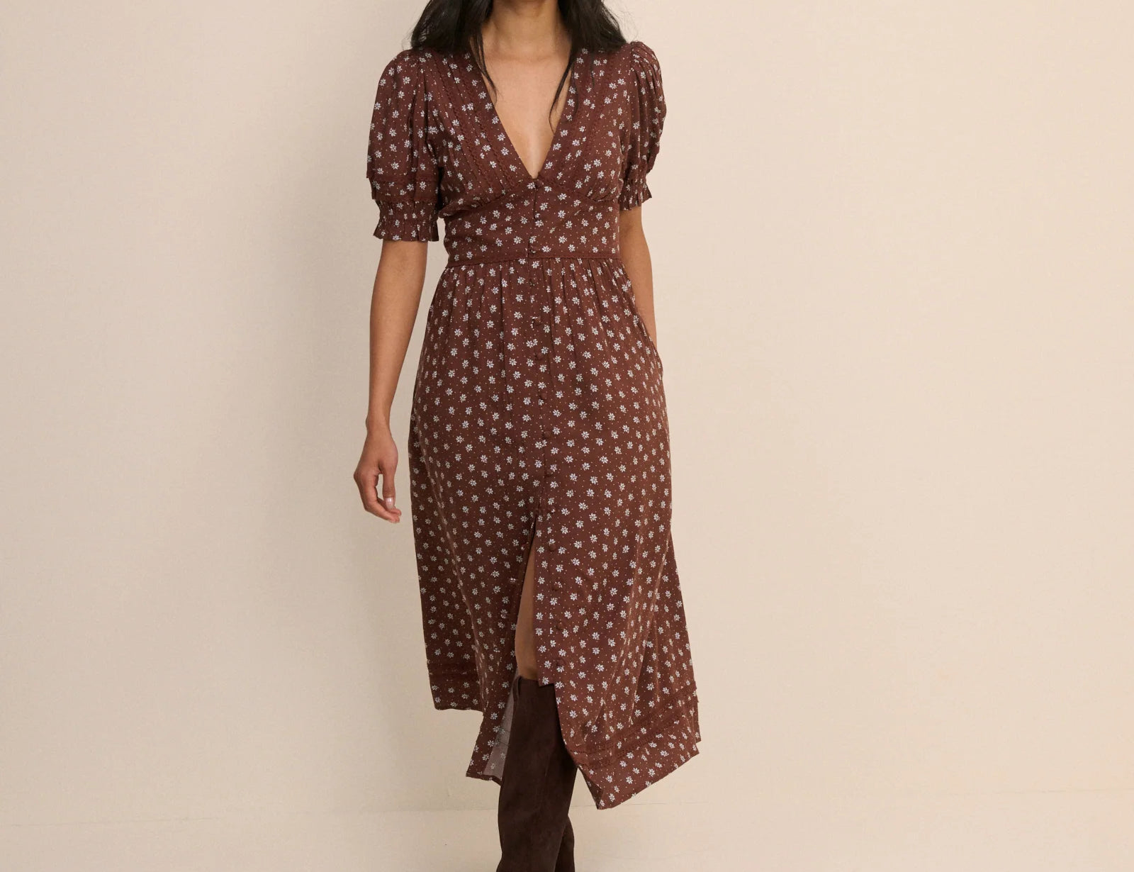 Woman wearing a brown patterned dress against a beige background