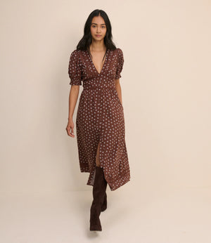 Woman wearing a brown patterned dress against a beige background