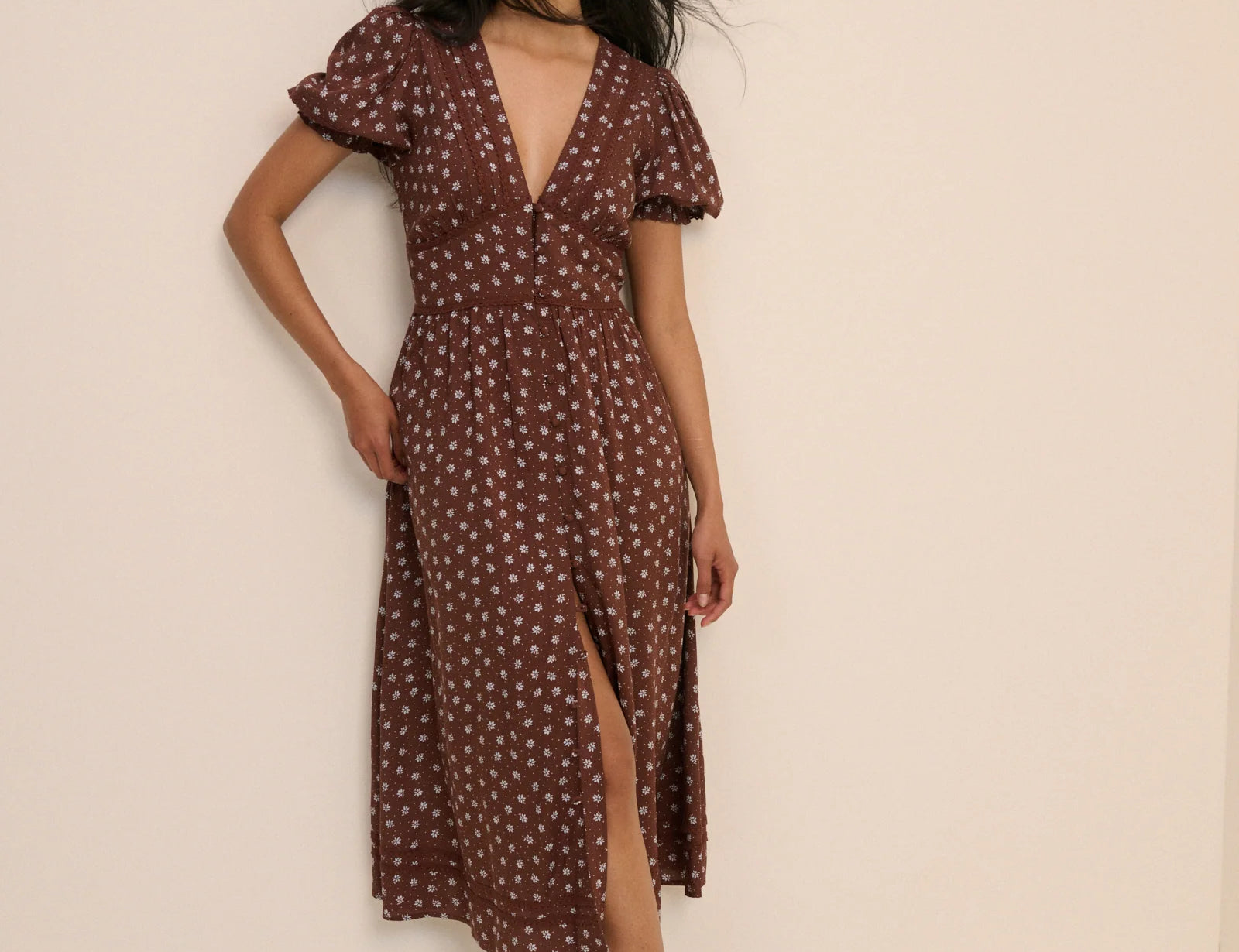 Woman wearing a brown dress with white patterns against a beige background