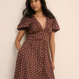 Woman wearing a brown floral dress against a beige background