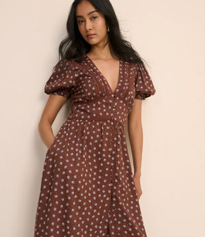 Woman wearing a brown floral dress against a beige background
