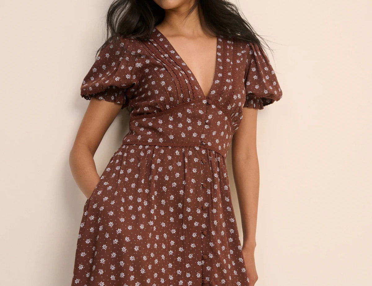 Woman wearing a brown floral dress against a beige background