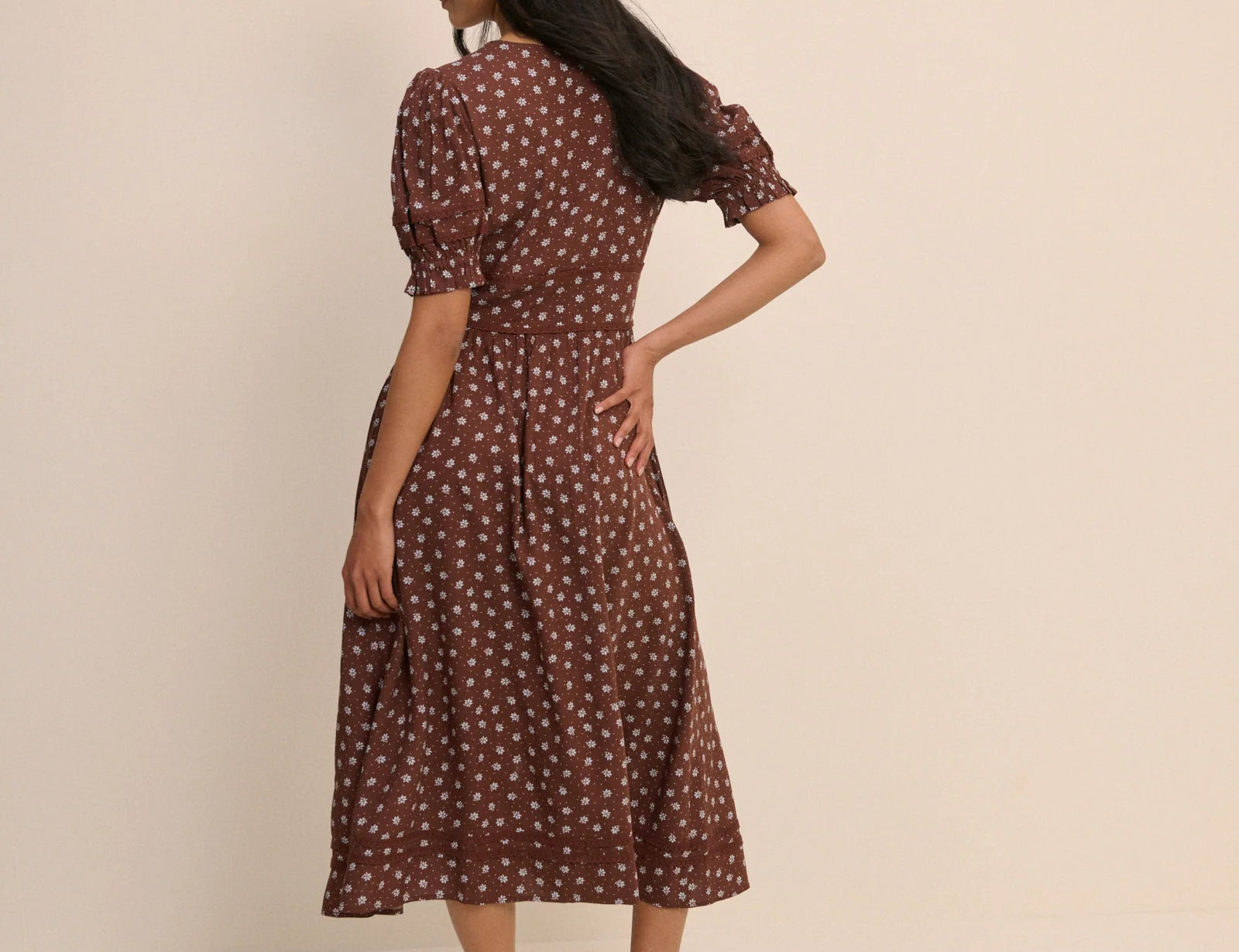 Woman wearing a brown polka dot dress against a beige background