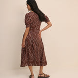 Woman wearing a brown polka dot dress against a beige background