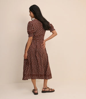 Woman wearing a brown polka dot dress against a beige background