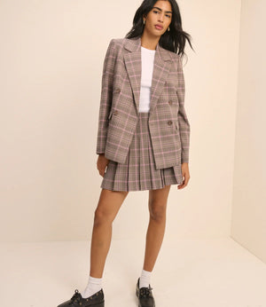 Woman wearing a plaid suit with a white shirt underneath on a beige background