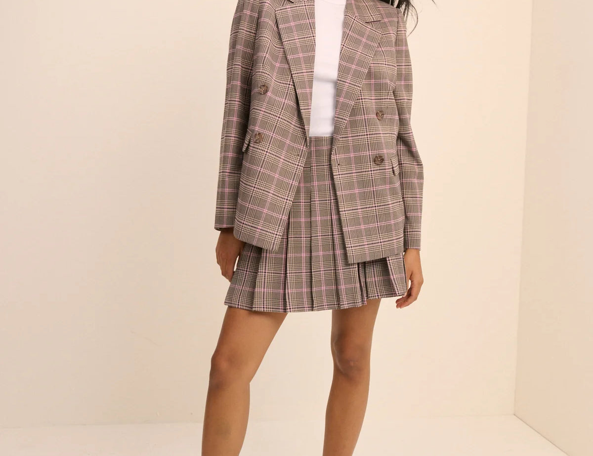 Woman wearing a plaid suit with a white shirt underneath on a beige background