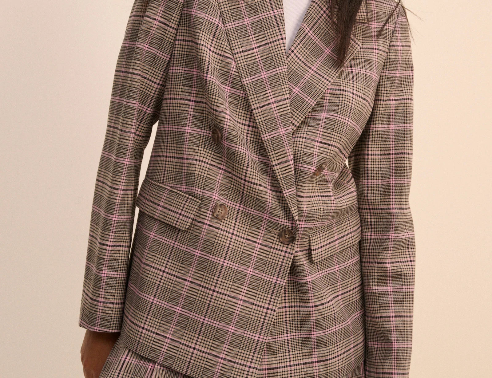 Plaid blazer and skirt set worn by a model on a beige background