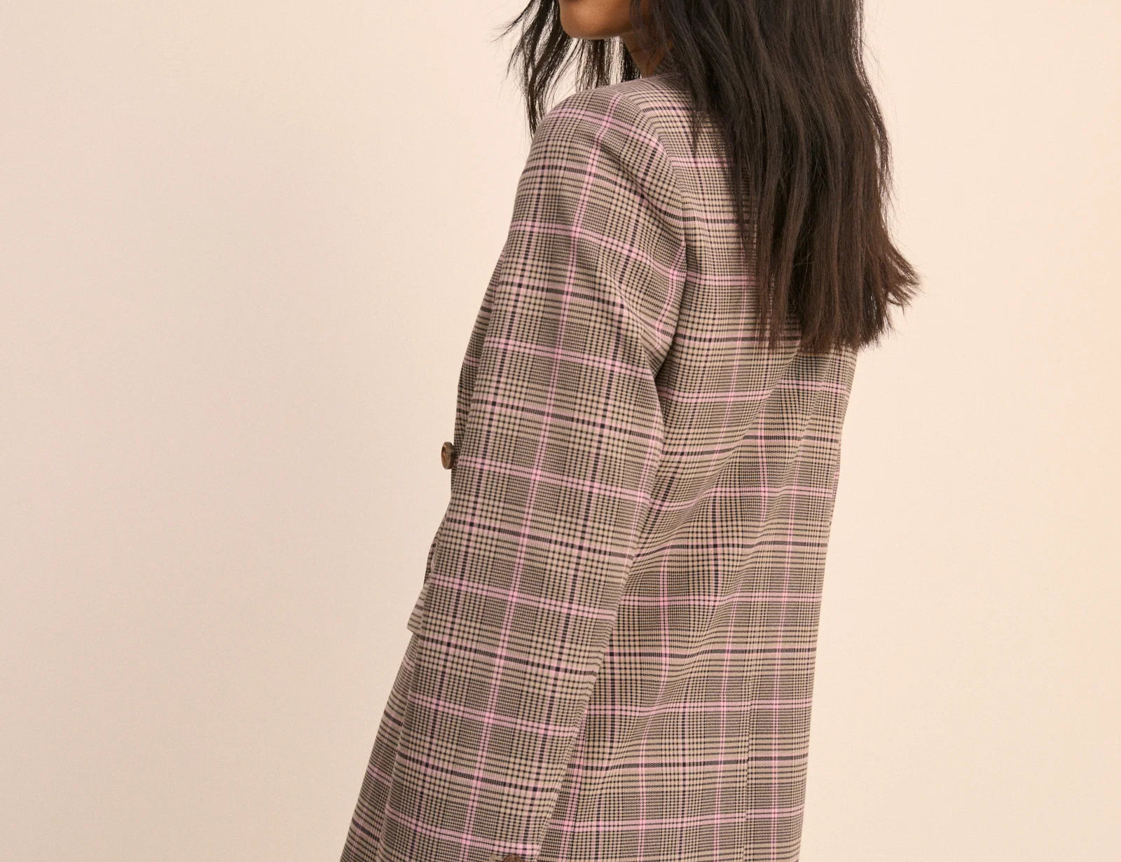 Woman wearing a plaid blazer and skirt set on a beige background