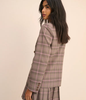 Woman wearing a plaid blazer and skirt set on a beige background