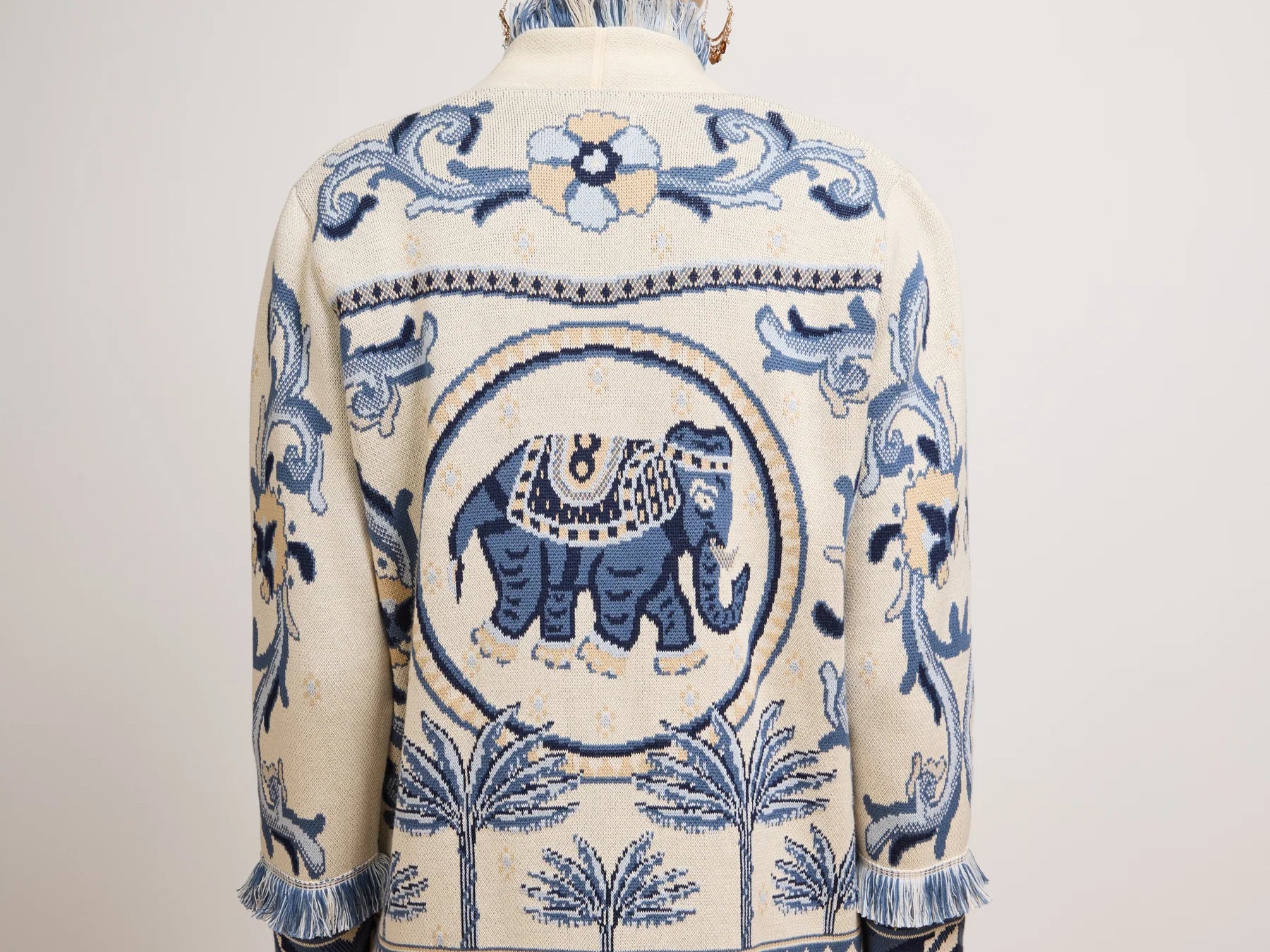 Man wearing a patterned jacket with an elephant design on a plain background