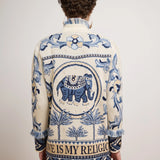 Man wearing a patterned jacket with an elephant design on a plain background