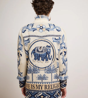 Man wearing a patterned jacket with an elephant design on a plain background