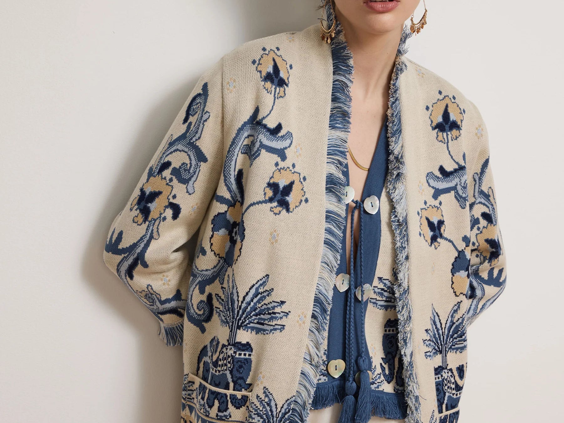 Woman wearing a patterned cardigan with a plain background