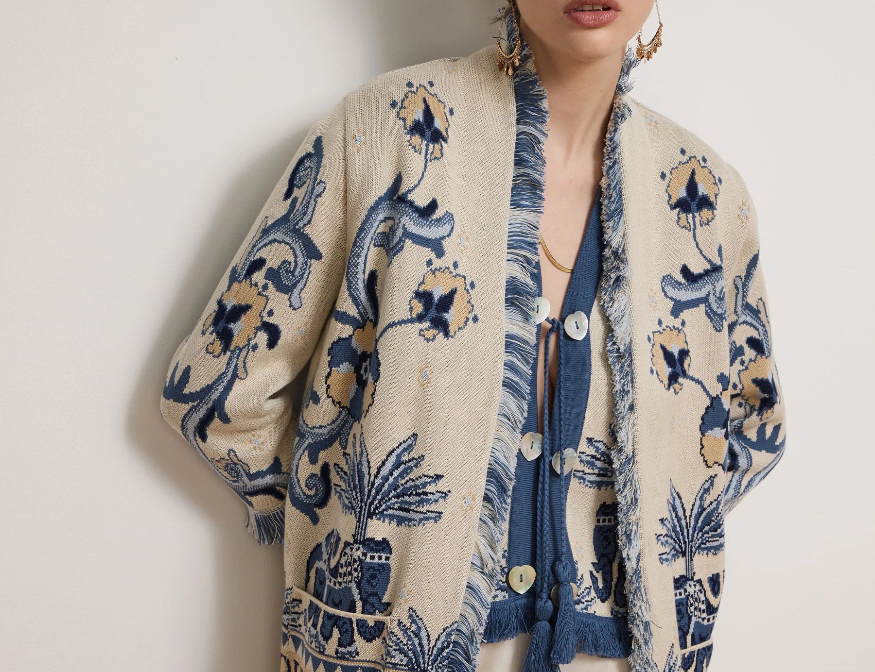 Woman wearing a patterned cardigan with a plain background