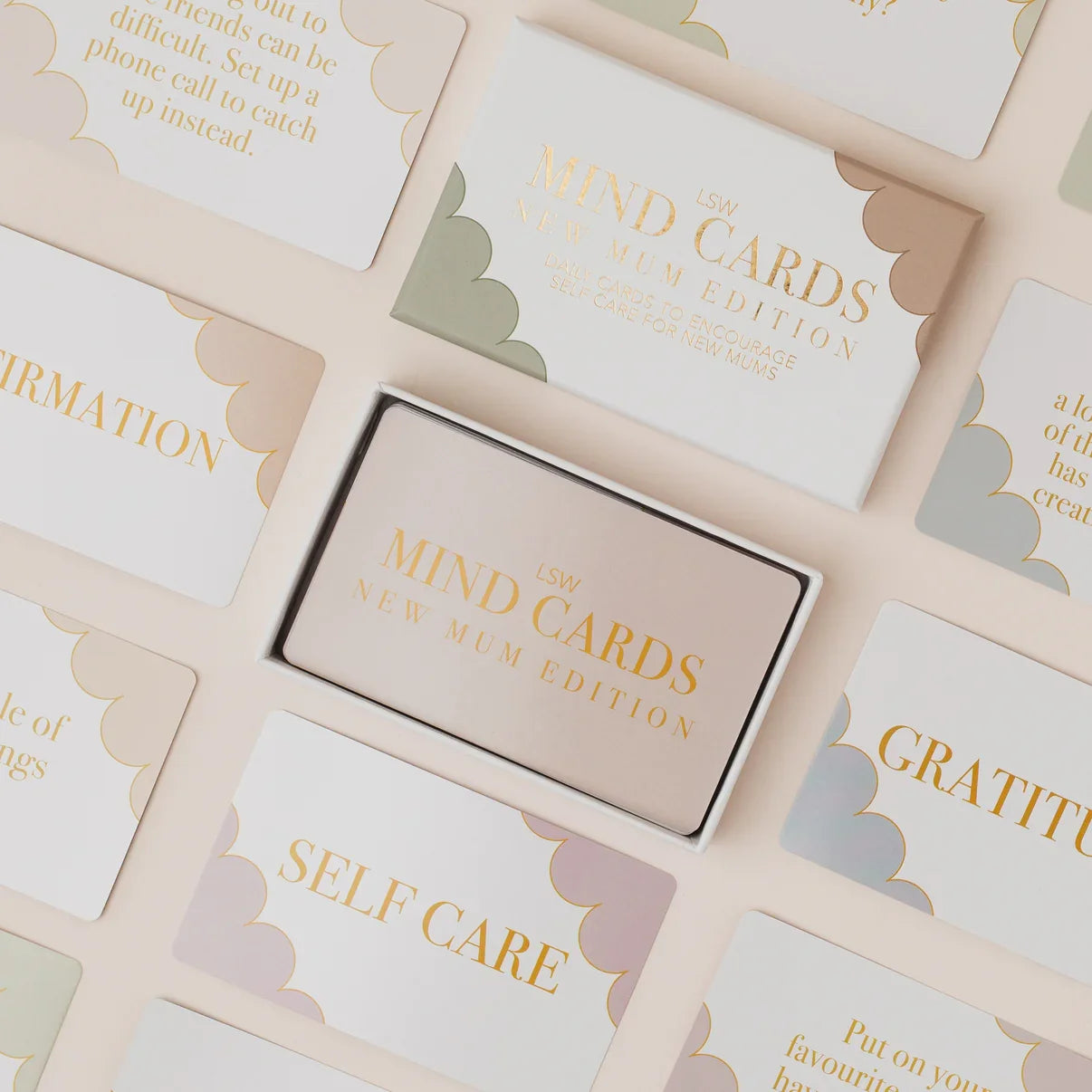 Box of 'The Mind Cards' on a surface with cards displaying text like 'Self Care' and 'Gratitude'.