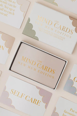 Box of 'The Mind Cards' on a surface with cards displaying text like 'Self Care' and 'Gratitude'.