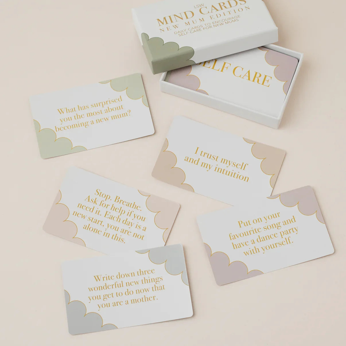 A set of white therapy cards with gold text and soft pastel cloud borders, arranged on a light beige surface with their white box partially visible at the top.
