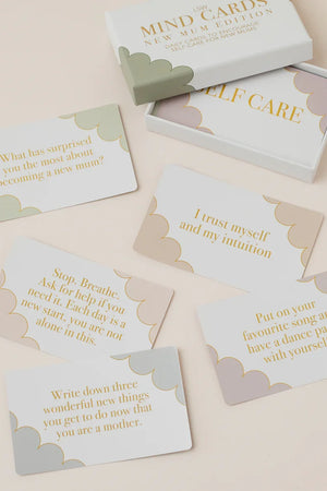 A set of white therapy cards with gold text and soft pastel cloud borders, arranged on a light beige surface with their white box partially visible at the top.