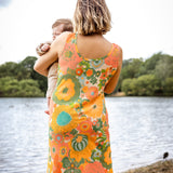 Woman in a floral dress holding a child by a lake