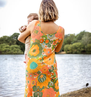 Woman in a floral dress holding a child by a lake