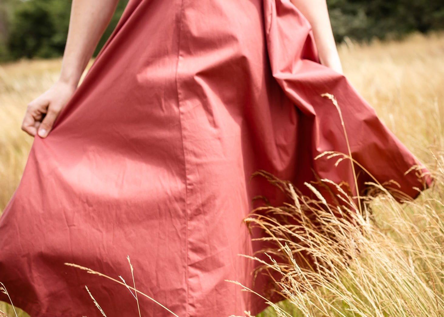 Person wearing a pink dress standing in a field of tall grass.